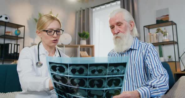 Female Doctor which Explaining the X-ray Scan to Her Old Bearded Male Patient During Home Visit