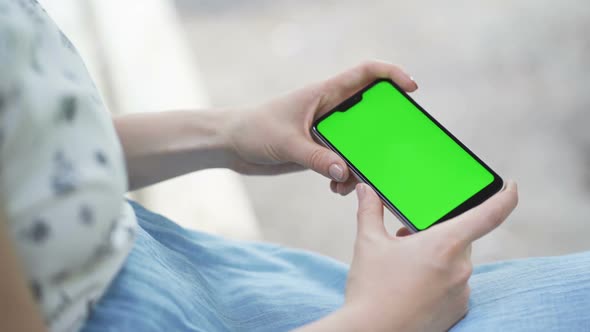 Beautiful Girl Holding in Her Hands a Smartphone with a Green Screen