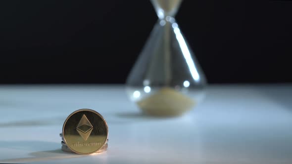 Hourglass and Digital Crupto Money on White Table. Time Is Money. Sand Pours. Black Background