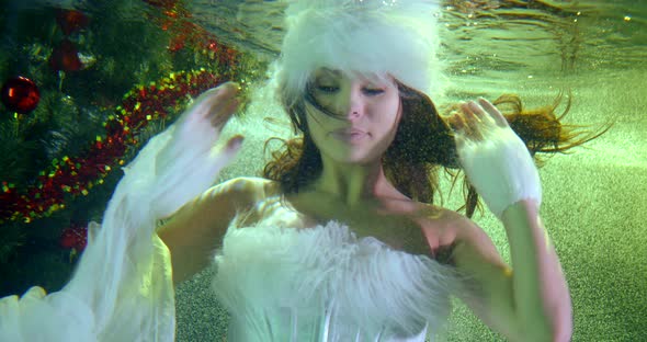 Sexual Female Model Is Moving Hands Floating Underwater in Pool with Christmas Tree