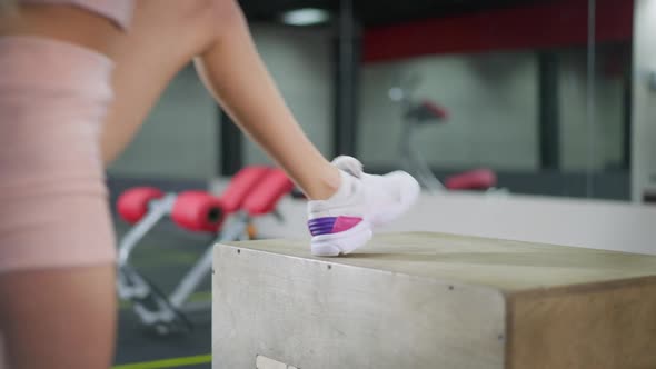 Slim Legs of Young Millennial Sportswoman Making Step Up Lunges on Gym Cube Indoors