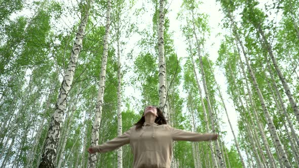 A Young Woman Spins in a Birch Forest. The Girl Is Glad To Be in Nature. 
