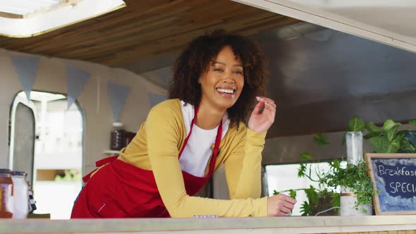 Portrait of african american woman wearing apron smiling while standing in the food truck
