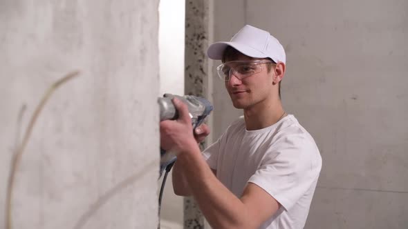 Master drills a hole in a concrete wall as part of finishing work in apartment