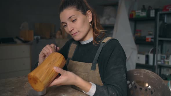 Craftswoman applying varnish on wood in workshop