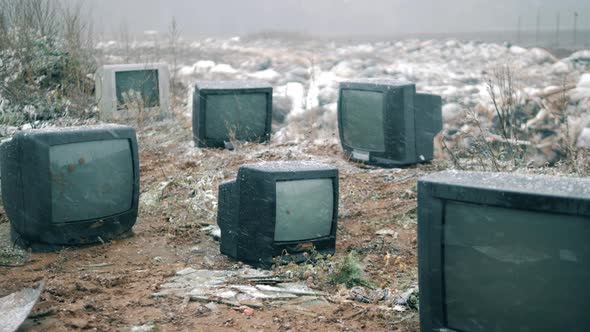 Broken TVs at the Landfill Site Under Falling Snow