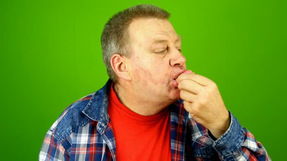 Senior Adult Caucasian Ethnicity Man Greedily Stuffs Into Mouth Cake with Cream Filling