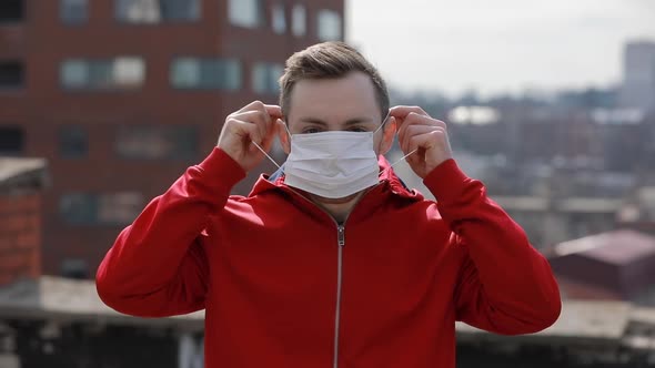 Covid-19 Virus Epidemic, Man Wearing Surgical Mask on the Roof of City