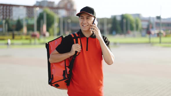 Male Courier With Isothermal Food Case Box Arrives to the Entrance to the House and Calls For Client