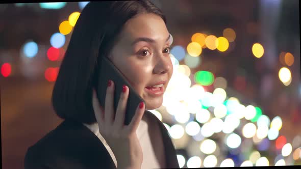 Asian young business woman standing outdoor using mobile phone downtown in city at night.