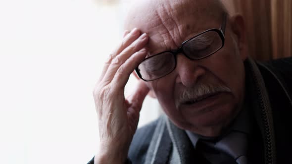 Close Up Portrait of Elderly Grandfather with Headache Senior Pensioner at Home