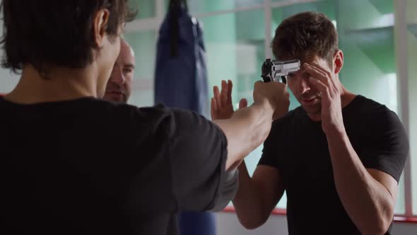 Two caucasian men learning self defense from trainer in gym