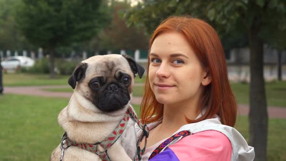 Girl Holding Her Pug and Smiling at Camera