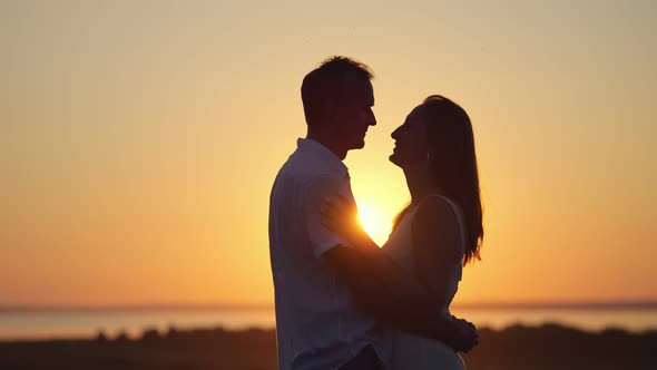 Couple Stands Showing Pure Love to Each Other at Back Sunset