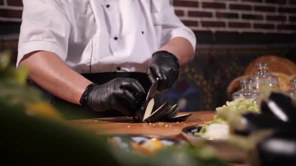 cutting vegetables eggplant, cook hands and knife