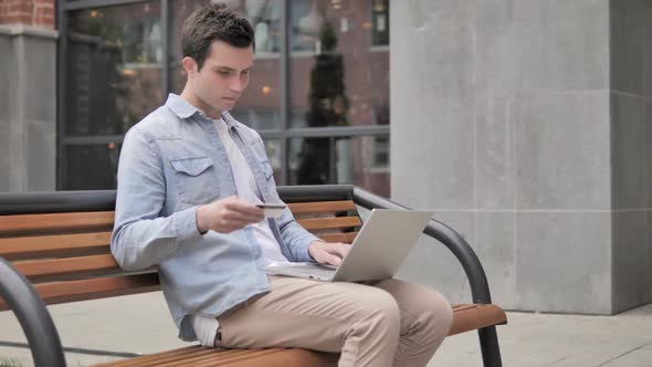 Online Shopping Failure for Young Man Sitting on Bench