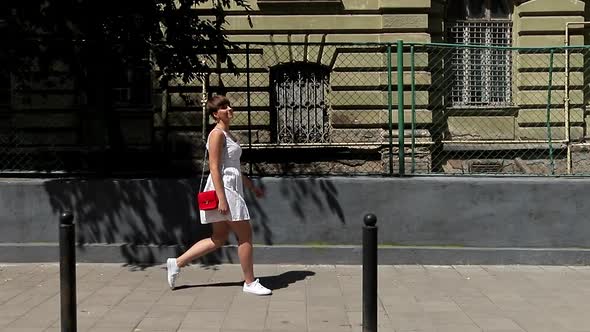 Beautiful Woman Smiling at Camera Enjoying Urban City Lifestyle. Young Funny Girl in a White Dress