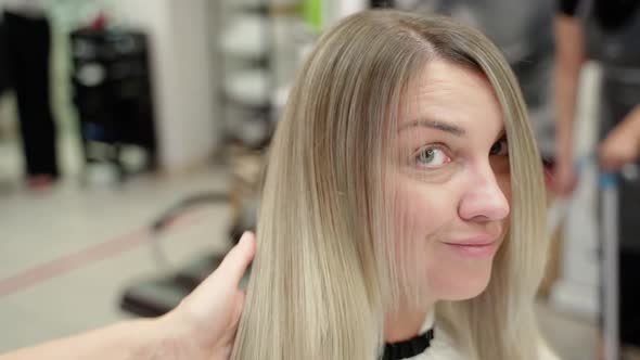 the Hairdresser Separates a Strand From the Face of a Beautiful Young Woman with a Thin Comb