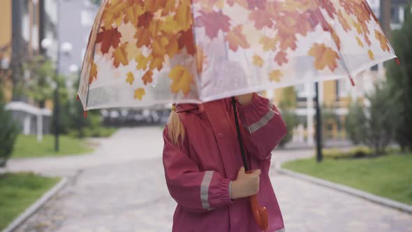Cheerful Little Caucasian Girl Spinning Umbrella Outdoors. Portrait of Smiling Cute Child Enjoying
