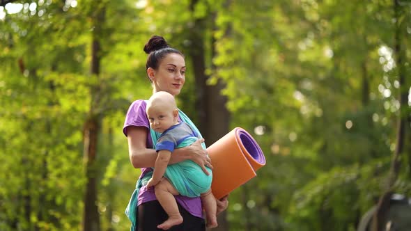 Yoga Woman Going To Outdoor Training with Baby in Sling