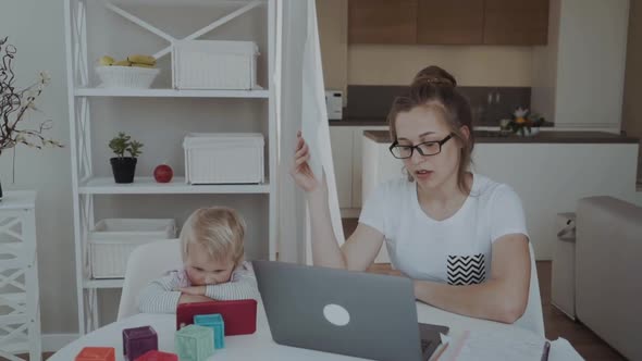 Unhappy Mother Working From Home Next To the Child