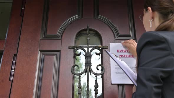 Civil servant, a woman in a jacket sticks a notice of eviction of the tenant