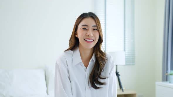 Portrait of Asian Beautiful girl in pajamas wake up early from bed, smile and look at camera.