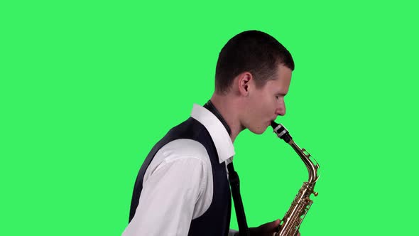 Portrait Stylish Young Guy Plays at Saxophone on a Green Screen in the Studio. Saxophonist