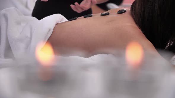 Woman having hot stone massage on back at spa