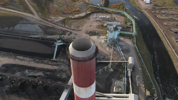 Red and white cooling tower of power plant next to blue river in the USA. Forward cameraement while