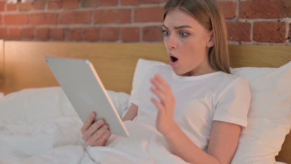 Disappointed Young Female Reacting To Loss on Tablet in Bed 