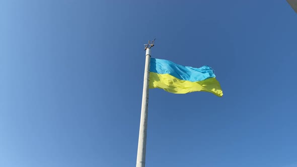 Ukraine national flag is waving in wind against blue sky. Big yellow blue patriotic Ukrainian state 