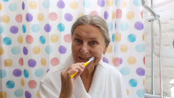 Portrait of Senior Woman Brushing Her Teeth in Bathroom at Home