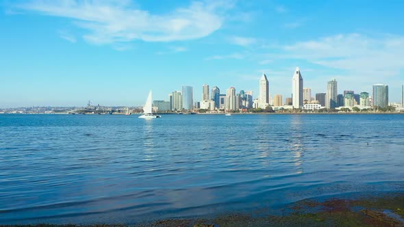 Aerial view of a sailboat on San Diego Bay with the city skyline in the background.