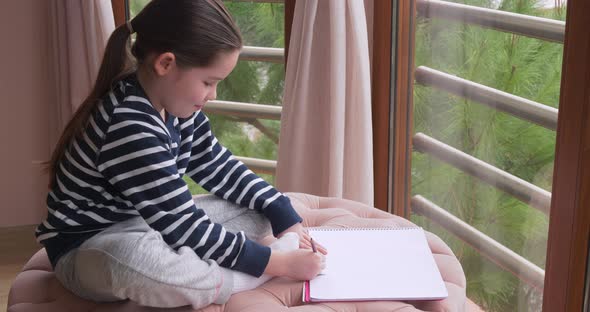 A Little Girl Drawing with Pencils at Home