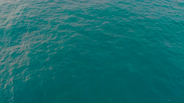 Open Waters Of Calm Blue Sea At Daytime Near The Island. - aerial tilt up