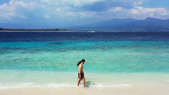 Teenage lovers tan on tropical coast beach adventure by aqua blue ocean and white sandy background o