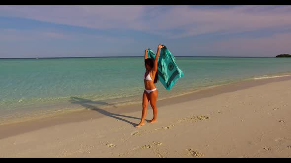 Single female relaxing on perfect seashore beach trip by blue green water with white sandy backgroun