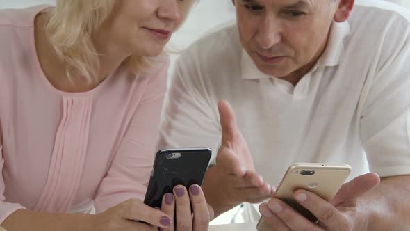 Husband and Wife Holds Phone, Watch at Screen, Talk with Smiles.