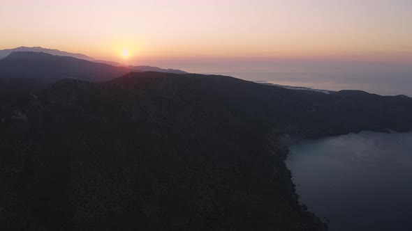 Aerial view of Sunrise above Coast line and Mountain. Flying over sea in the morning