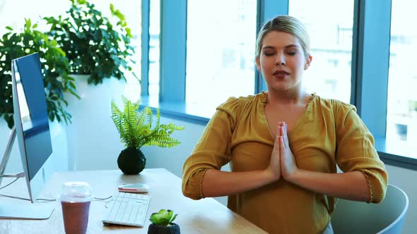 Female executive performing yoga at her desk