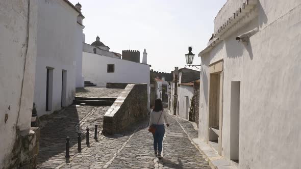 Woman walking in Monsaraz village street with white houses in Alentejo, Portugal