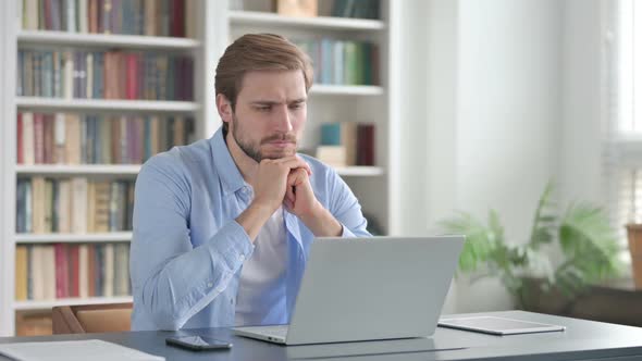 Man Thinking While Working on Laptop in Office