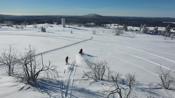 Aerial View of Winter Fun, Snow Scooter Towing Skier on Sunny Day, Drone Shot