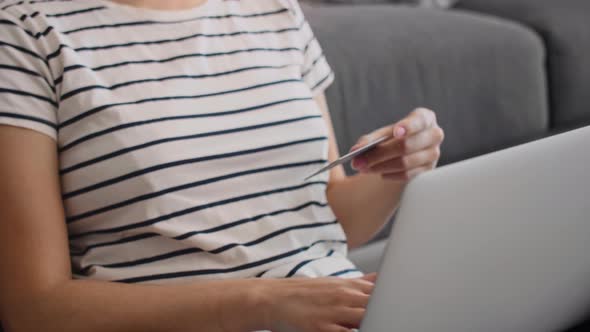 Tilt up video Asian woman using credit card in home