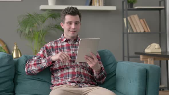 Man Talking on Video Call on Tablet on Sofa