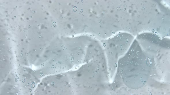 Transparent Blue Cosmetic Gel Fluid with Bubbles Flowing Down on a White Surface