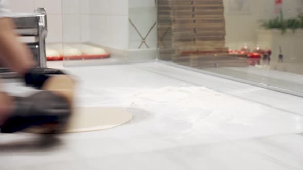 Professional Cook Rolls Out the Dough for Pizza Close Up