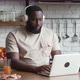 Bearded African American Man Freelancer in Headphones Eats Cookies and Works at the Computer While - VideoHive Item for Sale