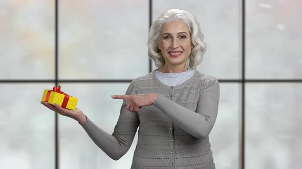 Mature Woman Pointing at Gift Box in Her Palm